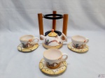 Jogo de 3 xícaras de chá com pires e 1 bule em porcelana, com suporte organizador de madeira. Um dos pires possui leves bicados, conforme retrata a imagem.