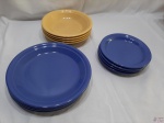 Jogo de 12 pratos em porcelana colorida, sendo 4 rasos azul (25,5cm), 4 fundos amarelo (22cm) e 4 de sobremesa azul (19,5cm). Um prato fundo está com bicado na parte inferior da borda.