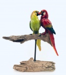 Escultura representando casal de araras repousando sobre tronco, confeccionada em resina de qualidade. Med. Alt. 30 cm. Comp. 28 cm.