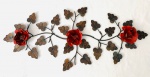 Adorno decorativo de parede em ferro, composto por três flores em tom vermelho e folhas. Med. 85x36 cm.