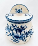 Saleiro de parede com tampa, decorado com pintura de flores à mão em tom azul, confeccionado em faiança. Med. 17x14 cm.