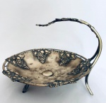 Antiga Fruteira de mesa redonda em metal decorada com cachos de uva em relevo, com quatro pés. Med. Alt. 20 cm. Diâm. 25 cm.