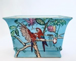 Lindo Cachepot em porcelana no tom azul, decorado com casal de araras vermelhas repousando sobre galhos. Med. 19x29,5x19,5 cm.
