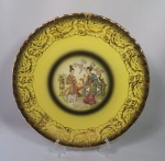 Belíssimo prato decorativo em porcelana Porcelanarte, borda e detalhes florais filetados a ouro, fundo amarelo, centro com cena de gueixas. Med. Diâm. 26 cm.