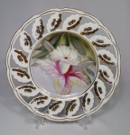 Belíssimo prato decorativo em porcelana, pintado à mão, com decoração floral e detalhes a ouro. Med. Diâm. 21 cm.