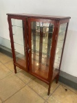 MOBILIÁRIO - Vitrine Chipandelle em madeira nobre com findo espelhado, 3 prateleiras internas, 2 portas centrais e laterais envidraçadas. Med. 136x100x40 cm. Pinos de sustentação das prateleiras adaptados de parafusos e possui uma ilumição interna, não original e não testada.