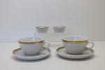 PORCELANA - Par de xícaras em porcelana branca com borda dourada e seus respectivos pires. Med. 5,5x10,5 cm. Acompanha 2 potinhos para manteiga individual.