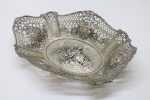 PRATA DE LEI - Belissímo cesto / centro de mesa em prata, teor 833 mls, contrastada, vazada, decorada com flores e ao centro cena galante. Med. 6x29x20 cm e peso 546 grs. PEÇA NÃO EXPOSTA NO LEILÃO, A MESMA ENCONTRA-SE NO COFRE DO BANCO.