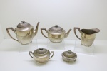 METAL - Jogo de chá e café em metal espessurado a prata, decorado com godrões, composto de: Bule de chá, bule de café, açucareiro e mantegueira. Maior 20 cm e menor 9 cm. Desgastes no banho.