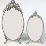Dois espelhos com moldura em prata de lei contrastada, ricamente cinzelada, no formato oval. Portugal. 34 e 27 cm de altura. Solicite o certificado de autenticidade da galeria Ricardo Von Brusky.