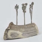 Porta petisco confeccionado em osso com 6 espetinhos em prata de lei representando figuras femininas e brasão. Medida espetinho: 9 cm; Porta petisco: 12 cm x 5 cm.