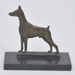 Escultura representando um cachorro em bronze com base em mármore.