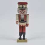 Boneco quebra nozes em madeira policromada representado soldado de guarda real na cor predominante vermelha. Década de 1950. Medida: 33 cm de altura