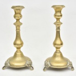 Par de castiçais em metal guilhochado apoiado sobre três pés em formato de folhagem em relevo. Império. Medida: 25 cm de altura x 11 cm