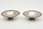 Duas pequenas fruteiras em metal espessurado à prata com bordas onduladas em gomos em relevo sobre base circular. Medida: 14 cm x 4,5 cm