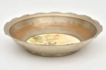 Cesta de pão em metal nobre alemão com fundo em faiança decorado por flores policromada. Apresenta marcas do tempo. Peça de coleção. Medida: 25,5 cm x 5 cm.