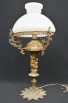 Elegante e grande abajur/luminária em bronze dourado ricamente cinzelado com figuras de crianças e cúpula em vidro opalinado em tom branco. Em bom estado de conservação. Medida: 64 cm de altura x 25 cm de diâmetro; 47 cm sem a cúpula. Ricamente trabalhado.