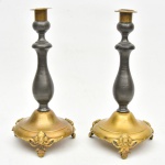 Par de castiçal em metal e bronze com base circular apoiado sobre três pés finalizados em garra e figura de leão. Medida: 24 cm x 10 cm