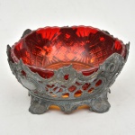 Fruteira em estanho/pewter ricamente fenestrado apoiado sobre 4 pés curvos terminados em volutas, acompanha bowl em cristal rubi em tom opalescente decorado por palmas e fundo estrelado. Em perfeito estado. Medida: 13 cm x 6 cm; Base: 14 cm x 7,5 cm
