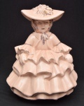 CERÂMICA ARTÍSTICA BARBOSA - Escultura em faiança esmaltada em tom rosa representando dama com vestido em babados, marca de sua manufatura em sua base. Medida: 28 cm x 20 cm