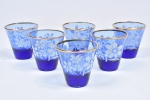 DÉCADA DE 1950 - Conjunto de 5 copos em demi cristal em tom azul royal com decoração floral  branca e borda com frisos dourados. Medida: 7 cm x 7 cm