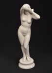 Escultura de biscuit branco representando figura feminina. Possui restauro. Medida: 28 cm x 8 cm de base.