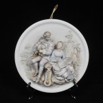Antiga, delicada e bela placa de parede em biscuit decorado por figuras em relevo adornado por casal galante em relevo em linda policromia. Peça de coleção. Medida: 27  cm de diâmetro; Obs: Falta um dedo na figura feminina;