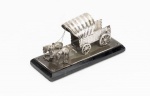 Miniatura de carroça de cavalos, marca Eberkoc, antiga, em metal banhado a prata, em base de madeira. Medidas aproximadas: 11,7 x 4,8 x 6 cm