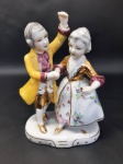 Pequena escultura feita em porcelana, representando casal de dançarinos com vestes típicas. MED.: 13X9CM