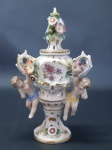 Pequeno e delicado ânfora em porcelana ricamente decorado com flores e anjos. MED.: 11cm Bicados.