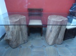 Grande mesa em vidro grosso esverdeado com base em toras de arvore. Mesa comporta 8 cadeiras.