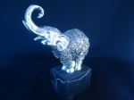 Belo Elefante em Resina espessurada a prata com base em madeira. Altura: 20 cm.