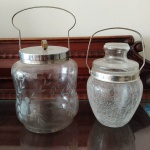 Duas biscoiteiras em vidro antigo decorado com tampo em metal prateado .  Mede: 19 cm e 17 cm.