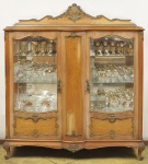 Cristaleira estilo francês Luis XV, em madeira clara e placagens em rádica. Composta de duas portas com cristal bisotado, encimada por florão. Medida 173 x 150 x 45 cm. O móvel apresenta desfolhamento.
