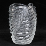 Magnífico vaso de cristal maciço europeu, trabalho em baixo relevo de forma espiral, intercalados por três faixas lapidadas com margaridas, pequeníssimos bicados na base, medida 24 x 14 cm.