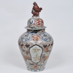 PEÇA NO ESTADO - Grande potiche com tampa de porcelana japonesa, decoração nos padrões Imari, século XIX. Adornado por quatro reservas com pinturas em sépia, tampa encimada por cão de fó, medida 65 x 34 cm.