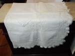 Toalha e 8 guardanapos, linho branco, borda rendada, centro da toalha rendada com flores. Pequenas manchas. 240 x 150cm e 28 x 28cm.