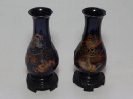 Par de vasos orientais, plástico rígido preto decorado em policromia de dragões. Alt. 21cm.