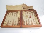 Maleta em madeira com jogo de gamão completo, composto por 15 peças claras, 15 escuras e 5 dados. Coleção Jogos da Terra. Fecho da maleta no estado.