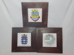 Três azulejos emoldurados em madeira apresentando escudos de instituições da Marinha Brasileira. Total 28 x 28cm.