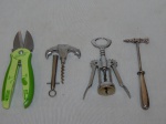 Quatro utensílios diversos: a) Abridor multiuso com lâmina, chave philips e tesoura. Manufatura Zibra. Comp. 20cm. b) Martelo para consumo de caranguejo em metal; Comp. 18cm. c) Abridor de vinho na forma de âncora em metal. 14cm. d) Abridor de vinho, mecanismo alavanca. Comp. 19cm.