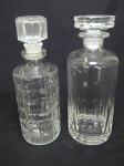 Duas garrafas em vidro, sendo uma francesa moldada com sulcos e blocos quadrados, alt. 26cm; e uma com facetados e lapidação com as iniciais "TR", alt. 26cm.