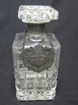 Garrafa em demi-cristal moldada com blocos em sequência no bojo e na tampa, aplicada com pórtico em metal prateado escrito "Whisky". Alt. 20cm.