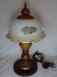 Abajur para 1 lâmpada, base em madeira torneada com parte em metal amarelo, cúpula em vidro leitoso branco decorado com arranjos florais pintados à mão, borda em babado. Alt. 46cm.