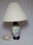 Abajur em porcelana branca, decorada com motivos florais em policromia, arte assinada por Moema, base e bocal em madeira torneada. Cúpula em acetato revestido por tecido. Alt. 51cm.