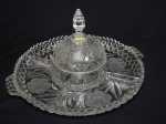 Petisqueira em cristal translúcido alemão, borda denteada, decoração com lapidações de folhagens e flores em satiné, 4 compartimentos, centro com compoteira com tampa, pega na forma de pinha facetada. 18 x 33cm.