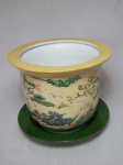 Cachepot em porcelana pintada à mão com animais em bosque sobre fundo amarelo. Acompanha presentoir verde. Fundo assinado por Moema. 19 x 23cm.