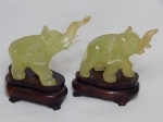 Par de esculturas representando elefantes confeccionadas em jade. Bases em madeira. Uma tromba com pequeno quebrado na ponta. Alt. 10cm.