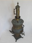Antigo samovar em metal amarelo decorado com volutas, acantos e florais, duas alças e 1 torneira. Apresenta desgastes do tempo e amassados. Alt. 88cm.