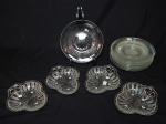 Doze peças em vidro translúcido: a) Oito pratos para sobremesa, lapidação de canelados estrleados. Diâm. 16cm. b) Quatro petisqueiras moldadas no feitio de trevas. 13 x 12cm.